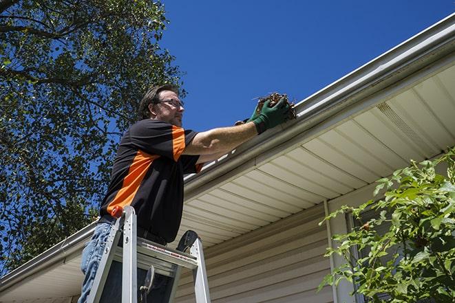 professional roofing crew repairing damaged gutter in Canadian Lakes MI